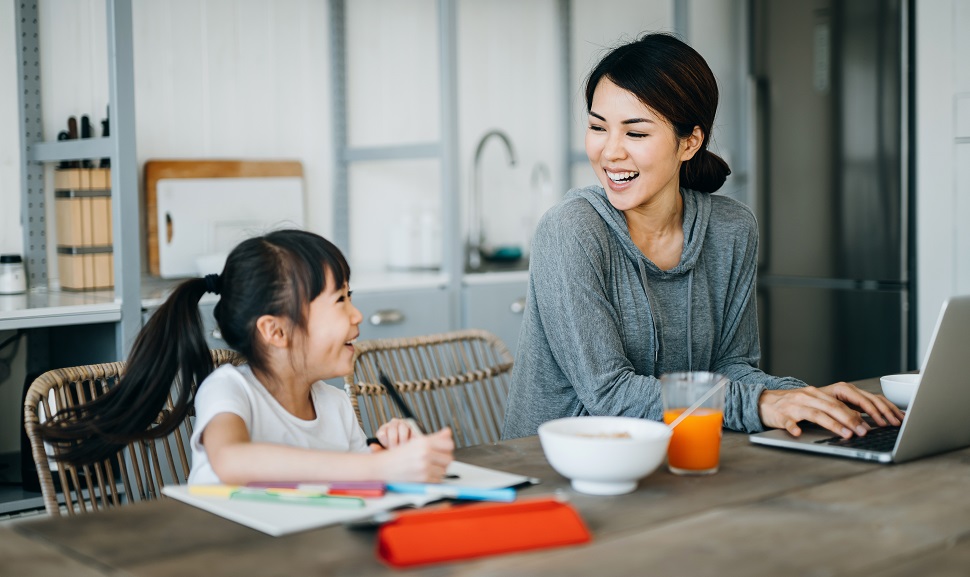 An Asian mum working at home while engaging her child