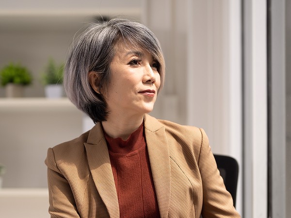 A lady in an office attire smiling with a blue gradient background.