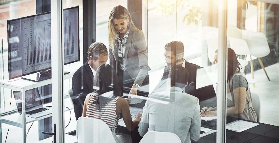 Office workers in discussion in an office setting | When to use a recruitment agency instead of hiring in-house