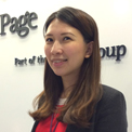Person smiling in front of company sign