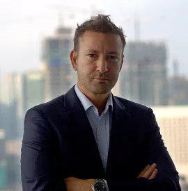 Person in a suit standing in front of a city skyline.