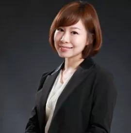 Person smiling in a professional suit against a dark background.