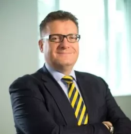 Person smiling, wearing a suit and striped tie