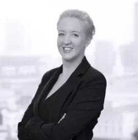 Person in a suit smiling in front of a city skyline.