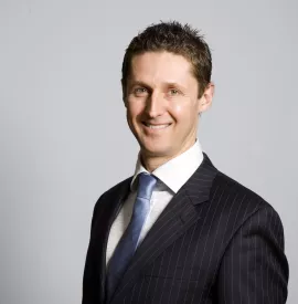 Person smiling, wearing a suit and tie.