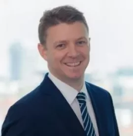 Person in a suit with a striped tie smiling.