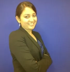 Person smiling in front of a blue background, wearing a formal outfit.