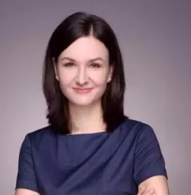 A person smiling at the camera in a formal setting.