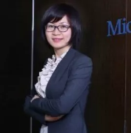 A professional standing in front of a wooden wall with a partial logo visible