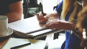 Group of people writing notes at a cafe
