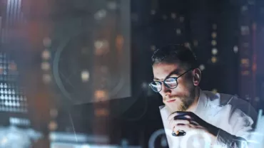 Person analyzing data charts on a computer at night