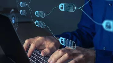 Hands typing on a laptop with blockchain icons visible.