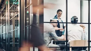 Group of people having a meeting in a glass-walled conference room.