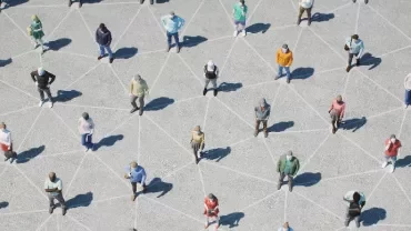 People standing apart in a geometric pattern on a plaza.