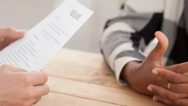 Close-up of a person holding a resume during an interview.