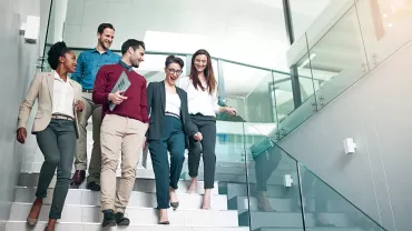Colleagues walking and chatting on office stairs.