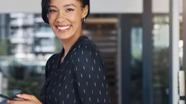 Person smiling while holding a phone in an office setting.