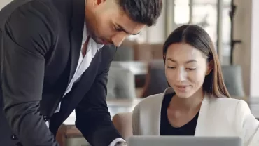 Two people discussing a project on a laptop in a cafe