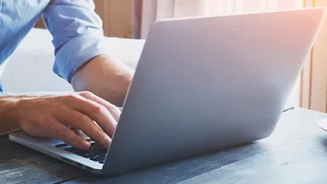 Person typing on a laptop with a cup of coffee on the table.