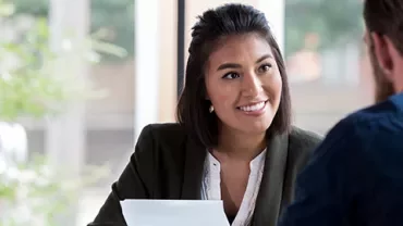 Two people having a conversation in an office with papers.
