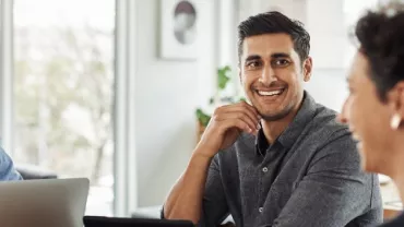 A group of people having a meeting in an office, smiling and conversing.