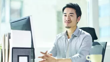 A professional sitting at a desk, smiling.