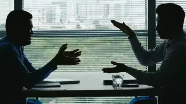 Silhouette of two business professionals engaged in conversation at a table, emphasising collaboration and discussion.