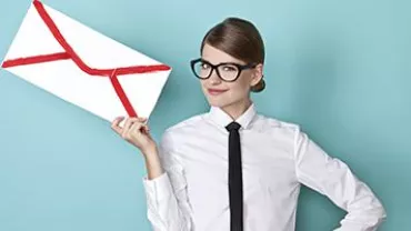 Person in white shirt holding large envelope against blue background.