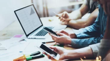 People at a desk using devices, possibly working.