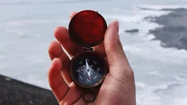 手持指南針，背景是大海