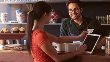 Customer and staff smiling during transaction in a cafe