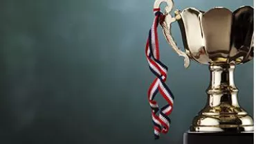 A gold trophy with a ribbon against a green background.