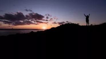 Silhouette of a person with raised arms at sunset