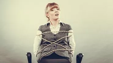 一位坐在椅子上的人被繩子綁住，看起來很不舒服。