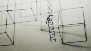 一個人在梯子上攀爬，背景是幾何形狀的結構。