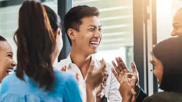 Group of people laughing and talking in an office