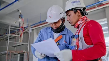 兩位工人戴著安全帽查看施工圖