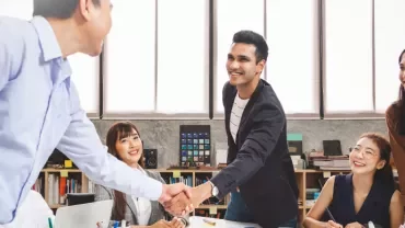 People shaking hands and smiling in a meeting room