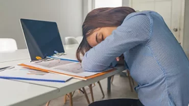 Person resting on a desk with head on documents