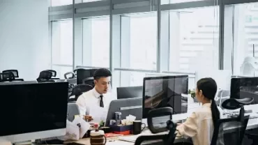辦公室內兩人坐在電腦前工作。