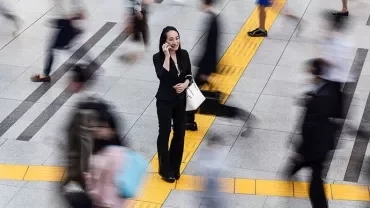 Person on phone in busy urban scene, surrounded by motion.