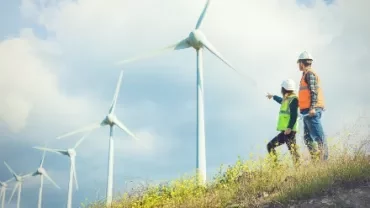 兩人在風力發電機旁的山坡上