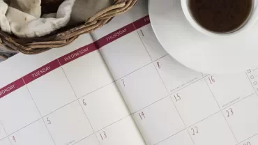 一杯咖啡和編織籃放在日曆上。