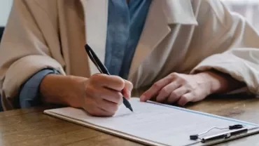 Person writing on a document at a desk.