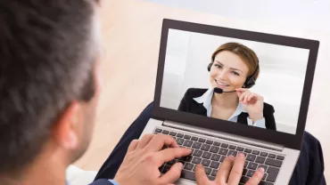 A person using a laptop for a video call, showing someone wearing a headset.