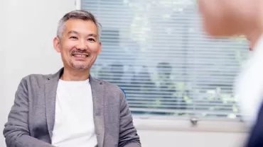 微笑的中年人在室內與他人交談