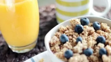 Bowl of granola with blueberries and a glass of orange juice