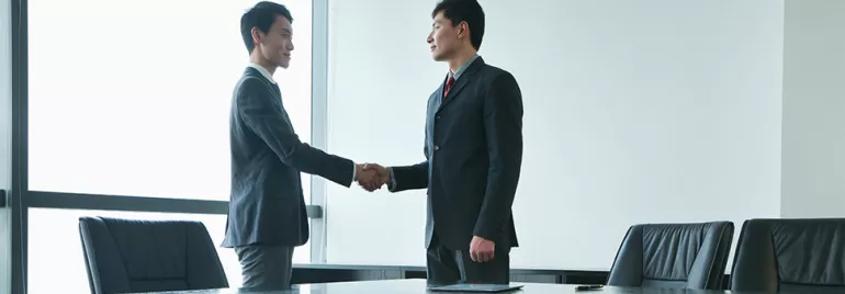 Two people shaking hands in a conference room