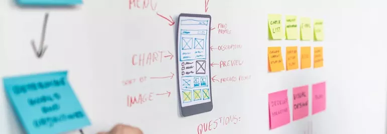 A whiteboard with a mobile interface sketch and sticky notes during a design meeting.