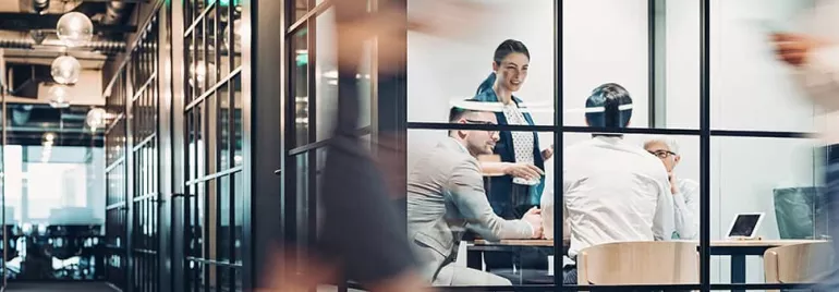 Group of people having a meeting in a glass-walled conference room.